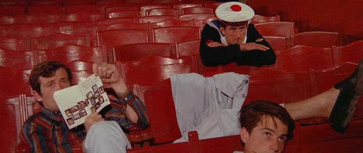 Tre män i röda stolar med blickarna mot filmduk